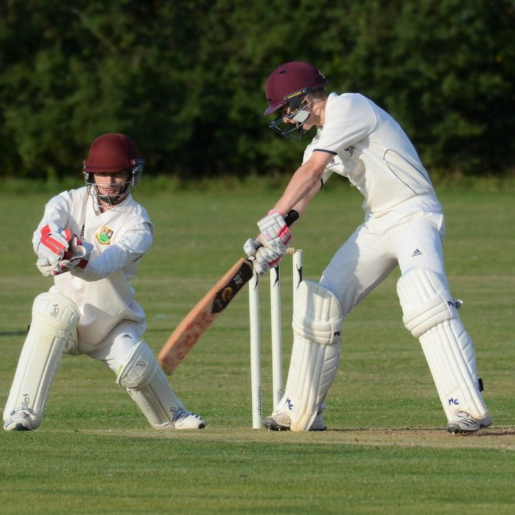 man in white jersey shirt and white pants holding baseball bat on green grass field during
